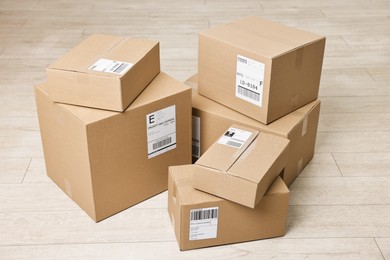 Photo of Cardboard parcel boxes with shipping labels on floor indoors