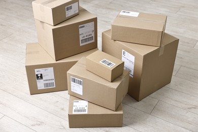 Photo of Cardboard parcel boxes with shipping labels on floor indoors