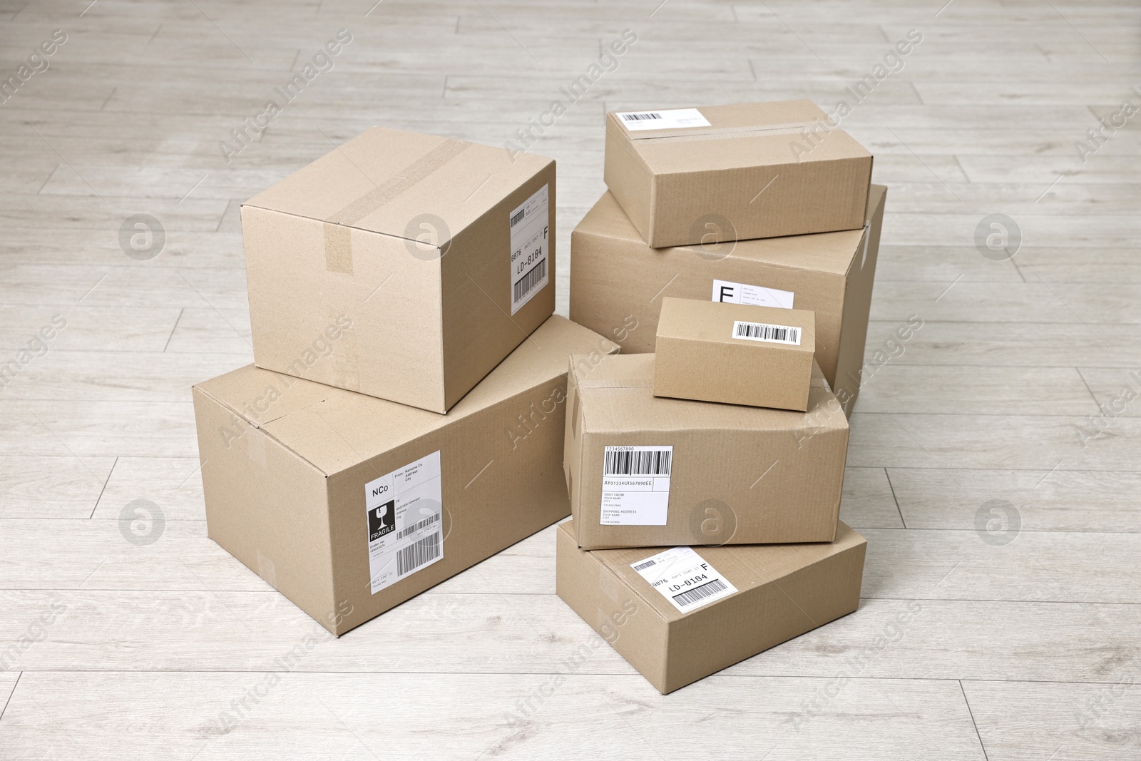 Photo of Cardboard parcel boxes with shipping labels on floor indoors