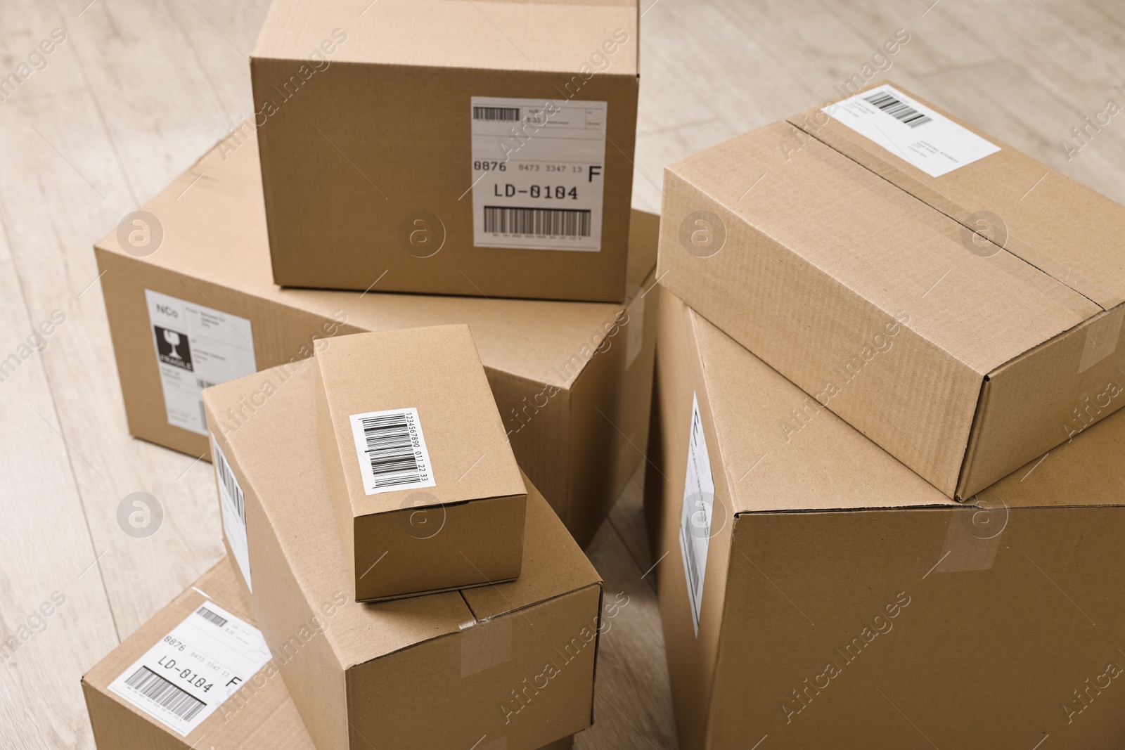 Photo of Cardboard parcel boxes with shipping labels on floor indoors, closeup