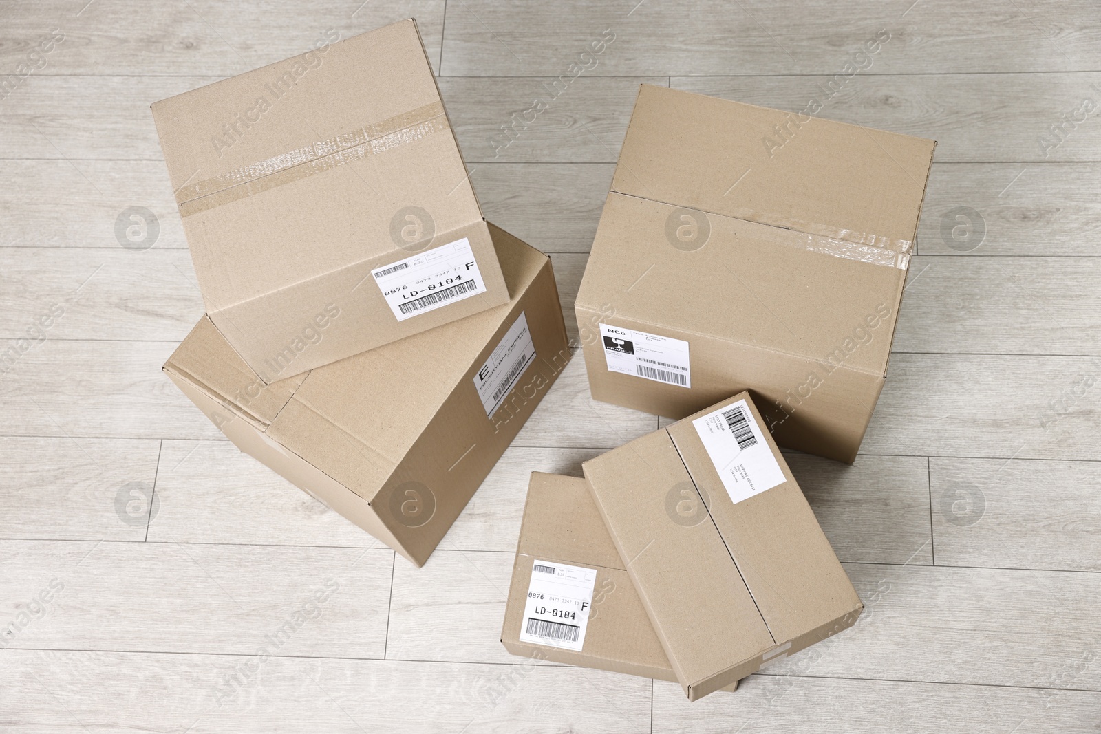 Photo of Cardboard parcel boxes with shipping labels on floor indoors, top view