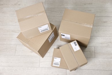 Photo of Cardboard parcel boxes with shipping labels on floor indoors, top view