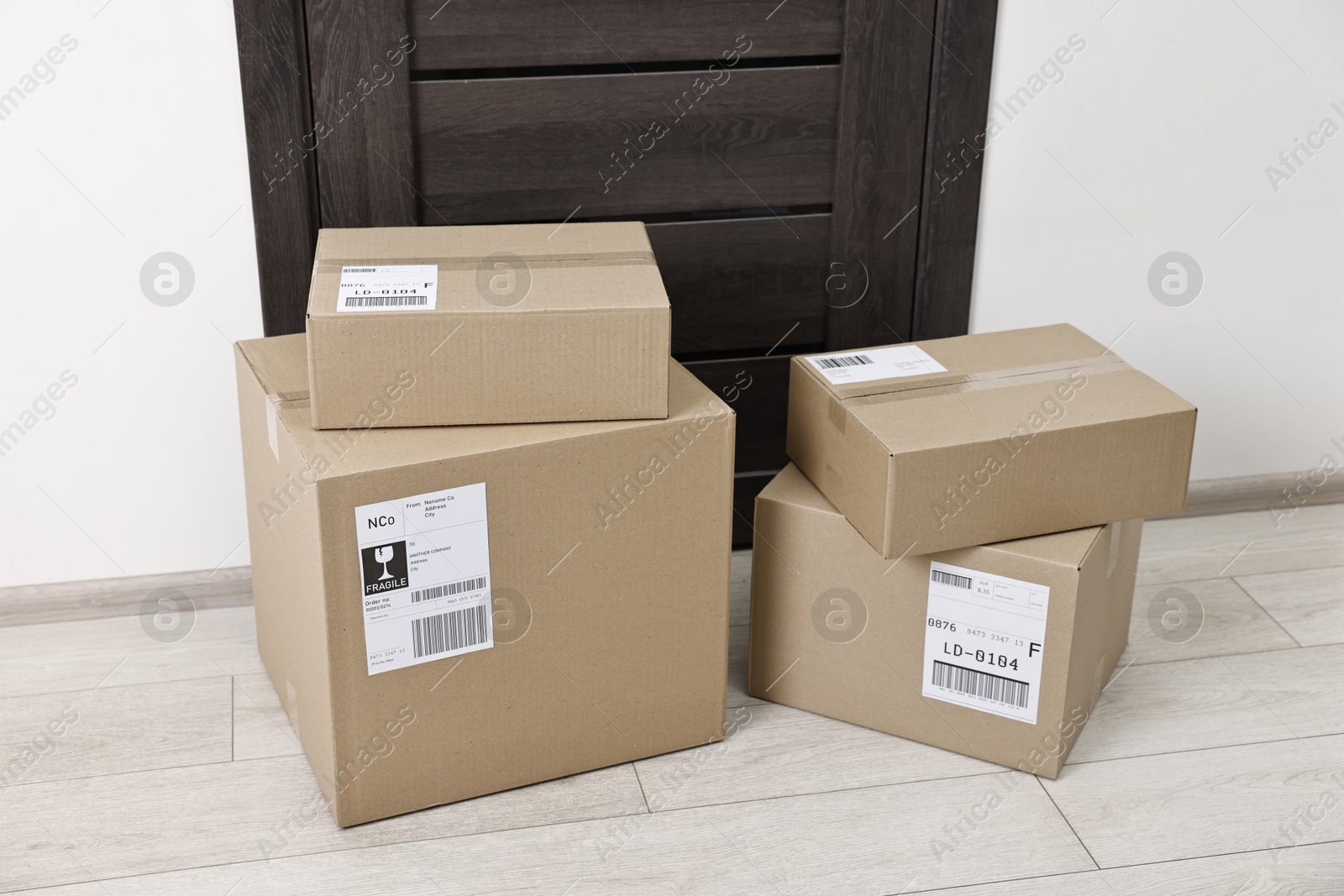 Photo of Cardboard parcel boxes with shipping labels near door indoors