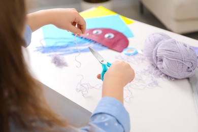 Photo of Little girl making craft at white table. Child creativity