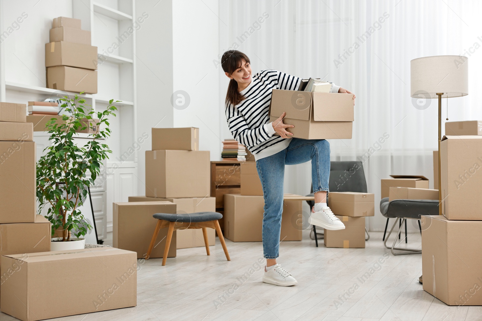 Photo of Moving day. Happy woman with her belongings in new home