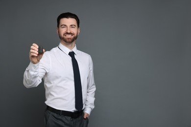 Photo of Cheerful salesman with car key on grey background