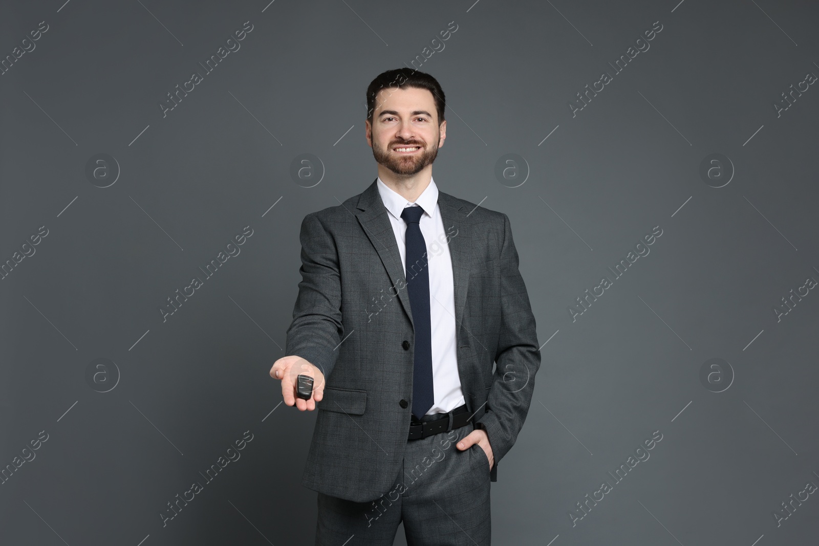 Photo of Cheerful salesman with car key on grey background