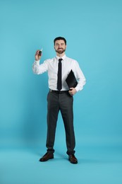 Photo of Cheerful salesman with car key and clipboard on light blue background