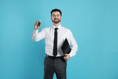 Cheerful salesman with car key and clipboard on light blue background