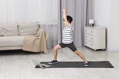 Photo of Little boy exercising near laptop at home. Morning routine