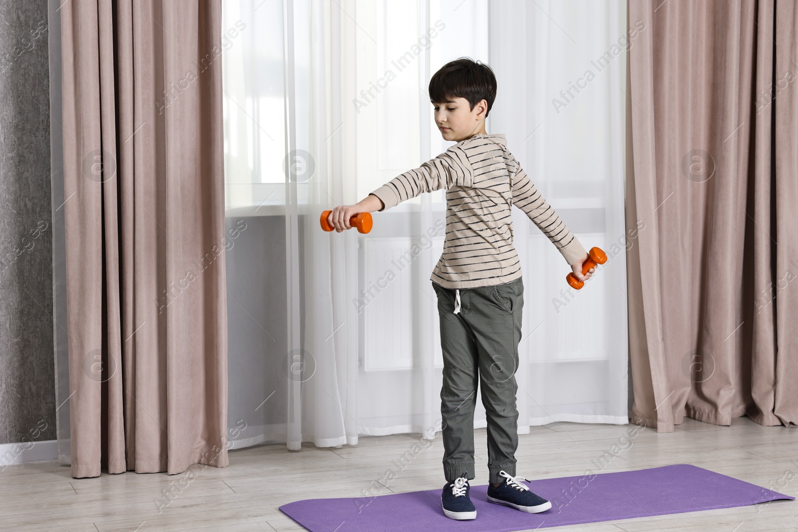 Photo of Little boy exercising with dumbbells at home. Morning routine