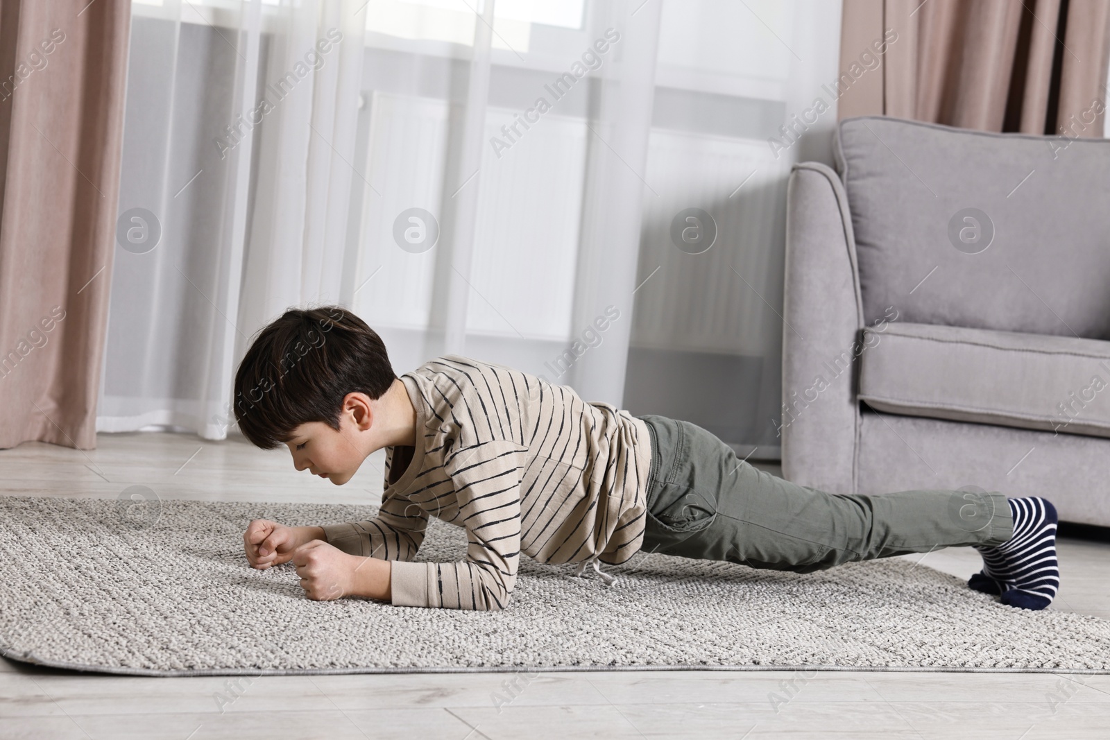 Photo of Little boy doing plank exercise at home. Morning routine