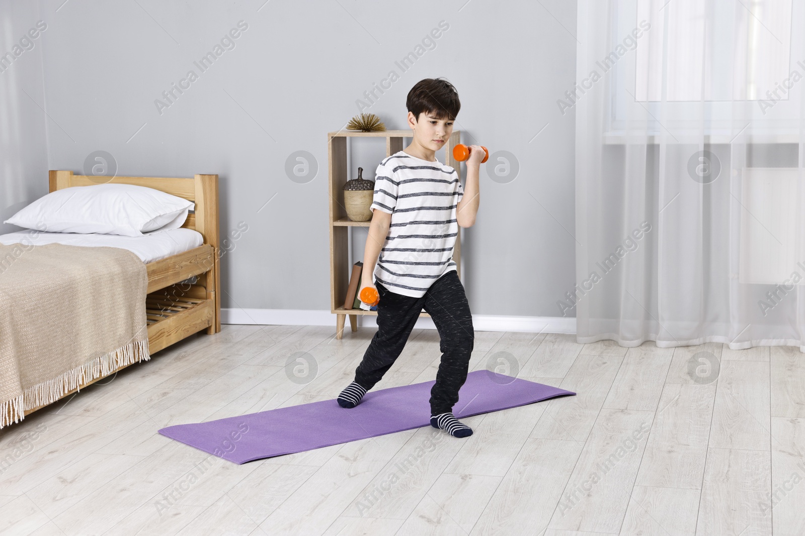 Photo of Little boy exercising with dumbbells at home. Morning routine