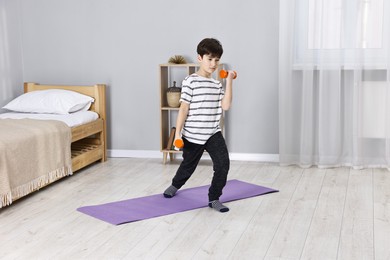 Photo of Little boy exercising with dumbbells at home. Morning routine