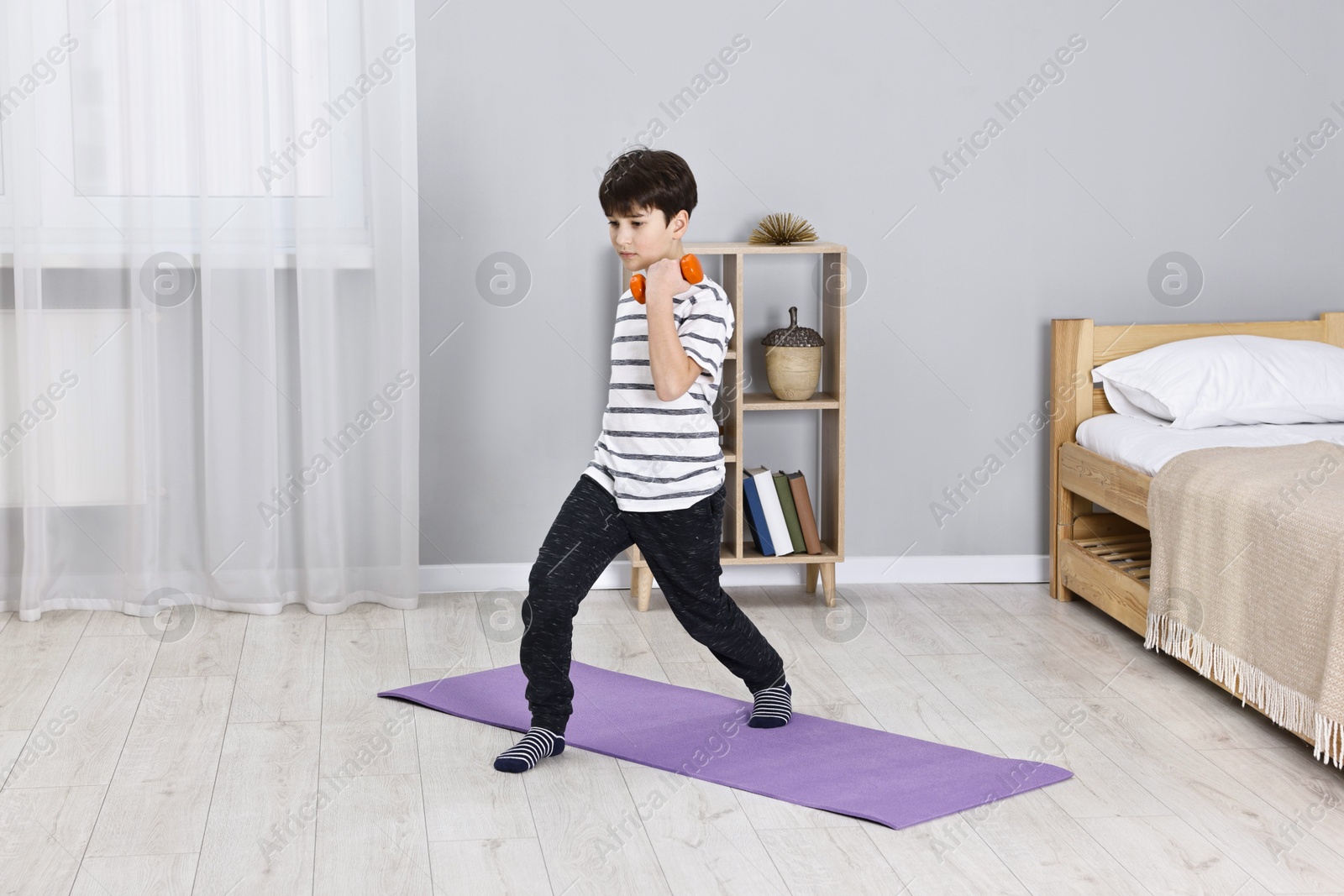 Photo of Little boy exercising with dumbbells at home. Morning routine