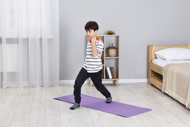 Little boy exercising with dumbbells at home. Morning routine