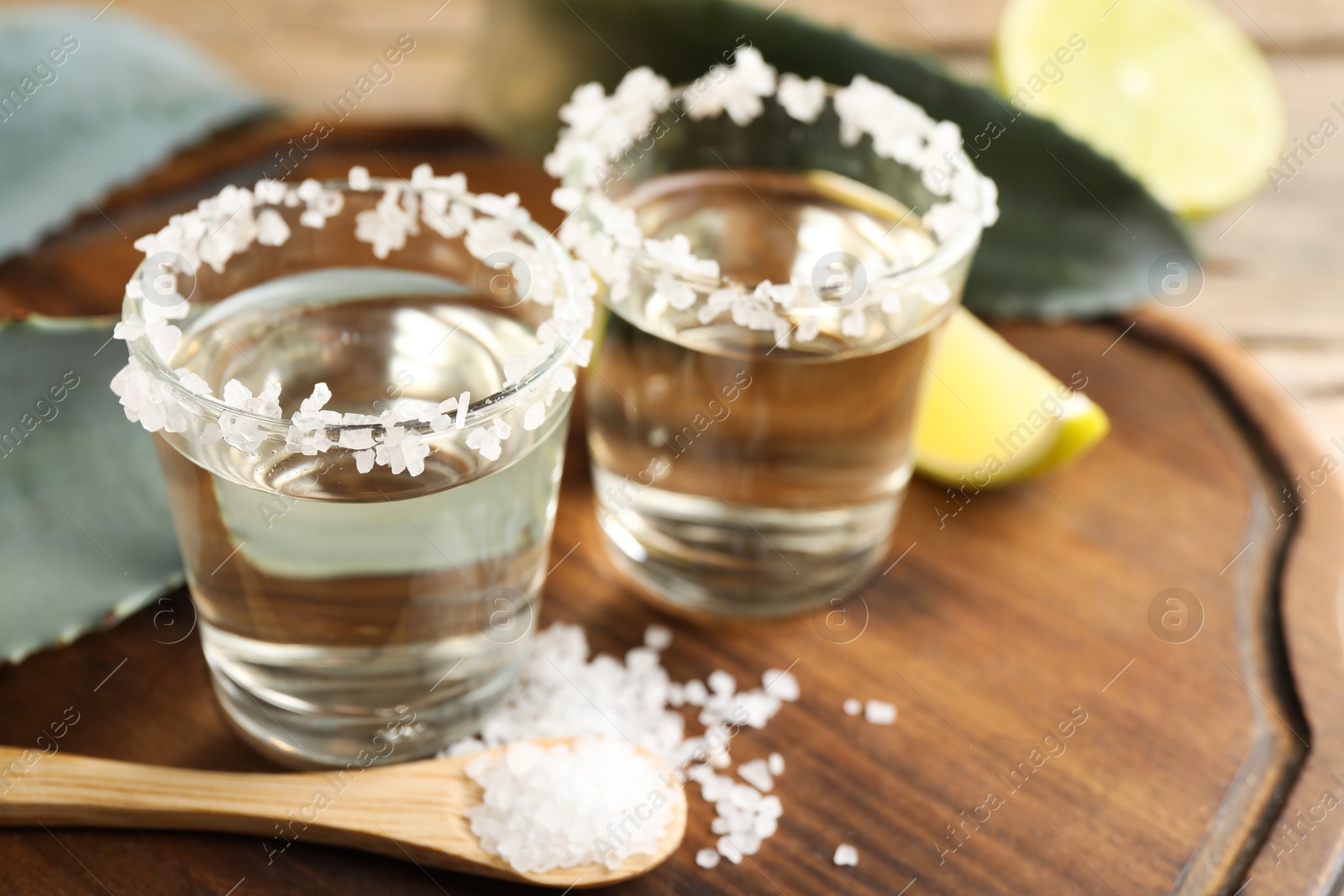 Photo of Tequila shots with salt on wooden table, closeup