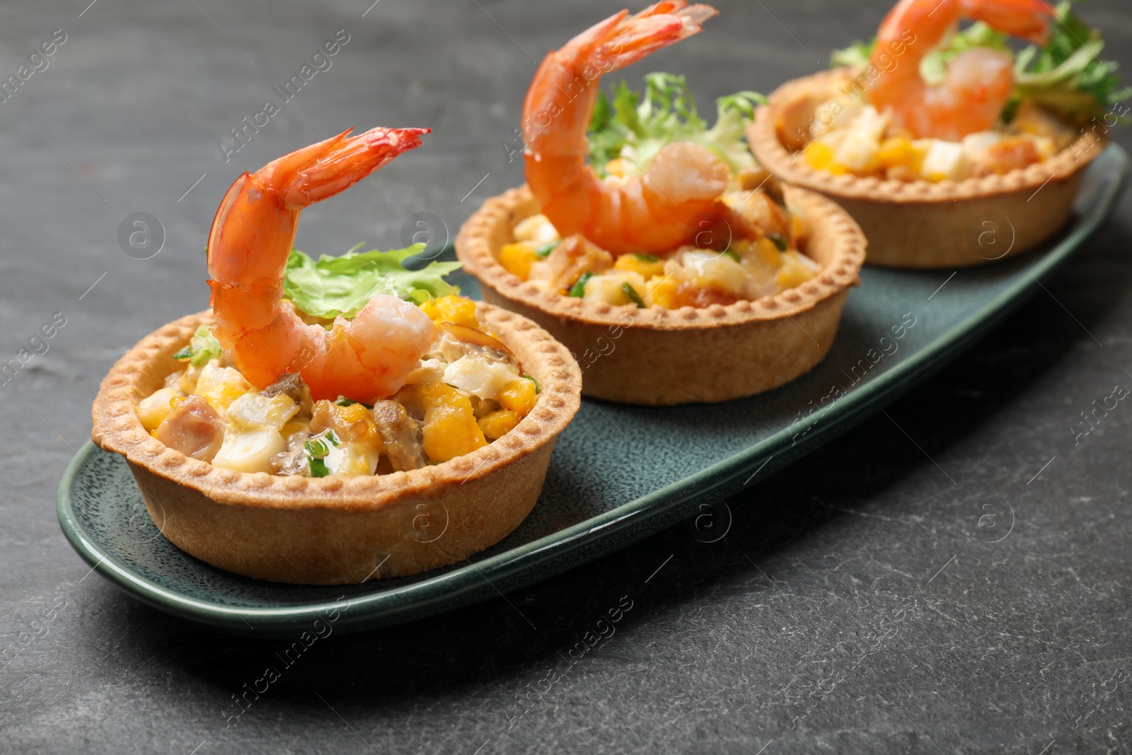 Photo of Tartlets with delicious filling on black table, closeup