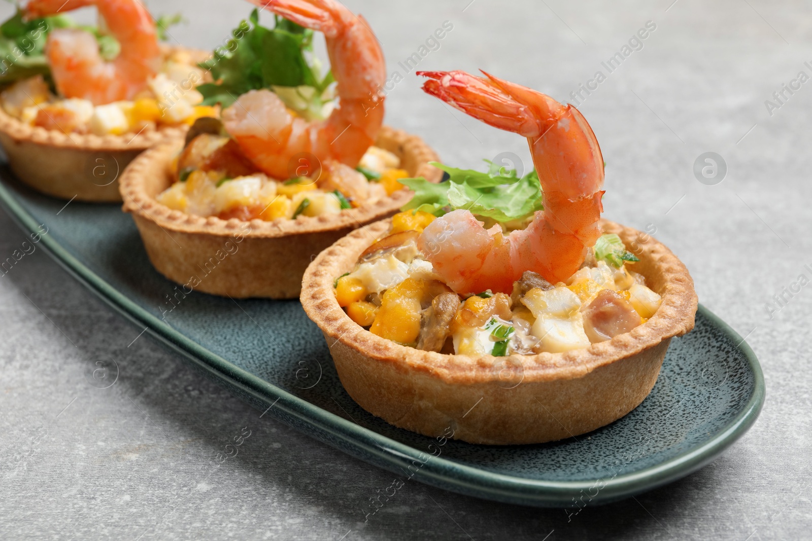 Photo of Tartlets with delicious filling on grey table, closeup