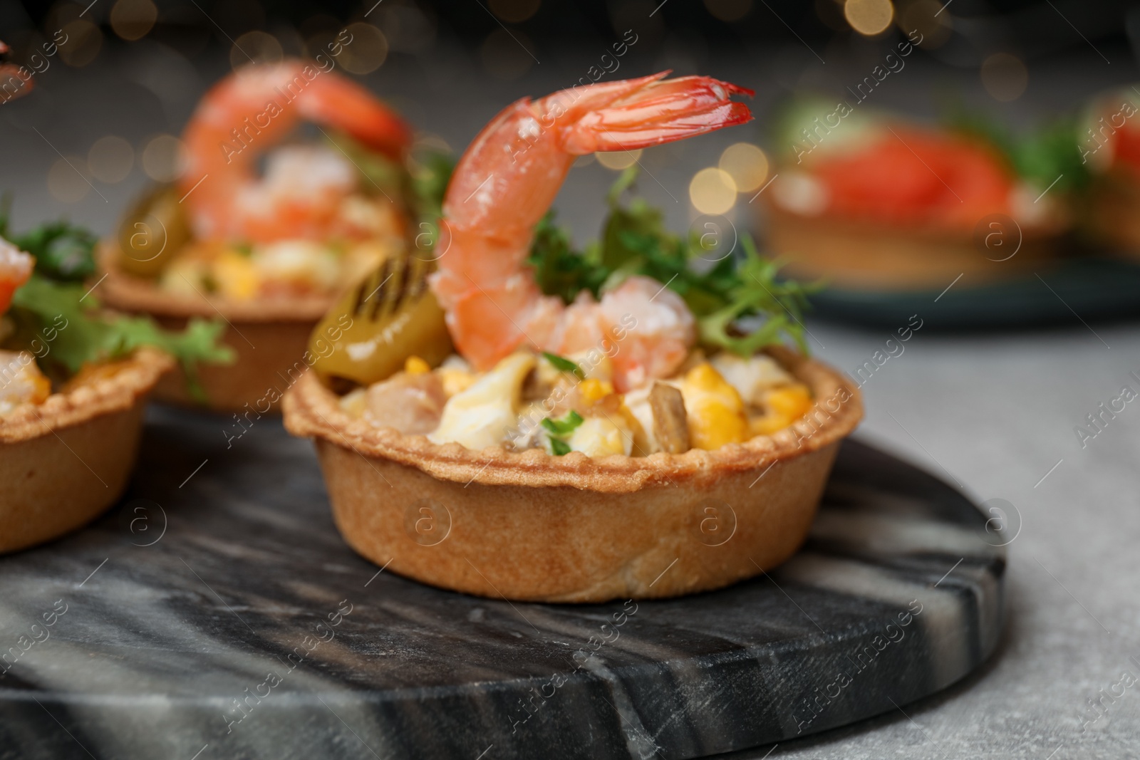 Photo of Tartlets with delicious filling on grey table, closeup. Bokeh effect