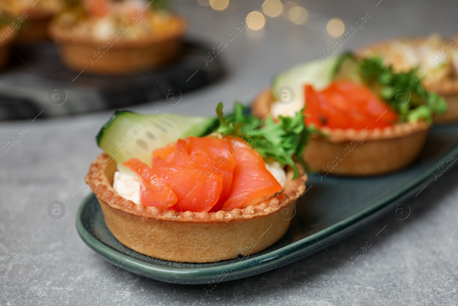 Photo of Tartlets with delicious fillings on grey table, closeup. Bokeh effect