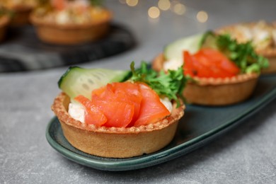 Tartlets with delicious fillings on grey table, closeup. Bokeh effect