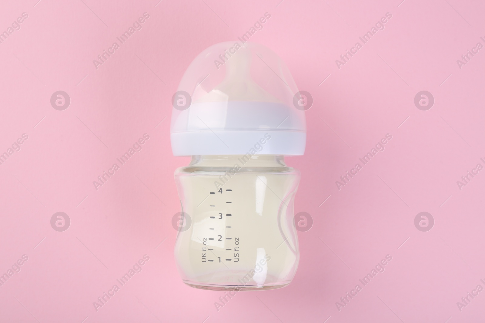 Photo of Feeding bottle with milk on pink background, top view