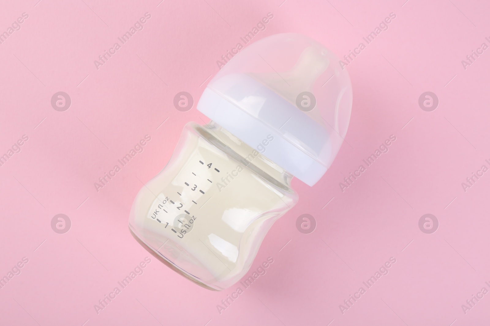 Photo of Feeding bottle with milk on pink background, top view