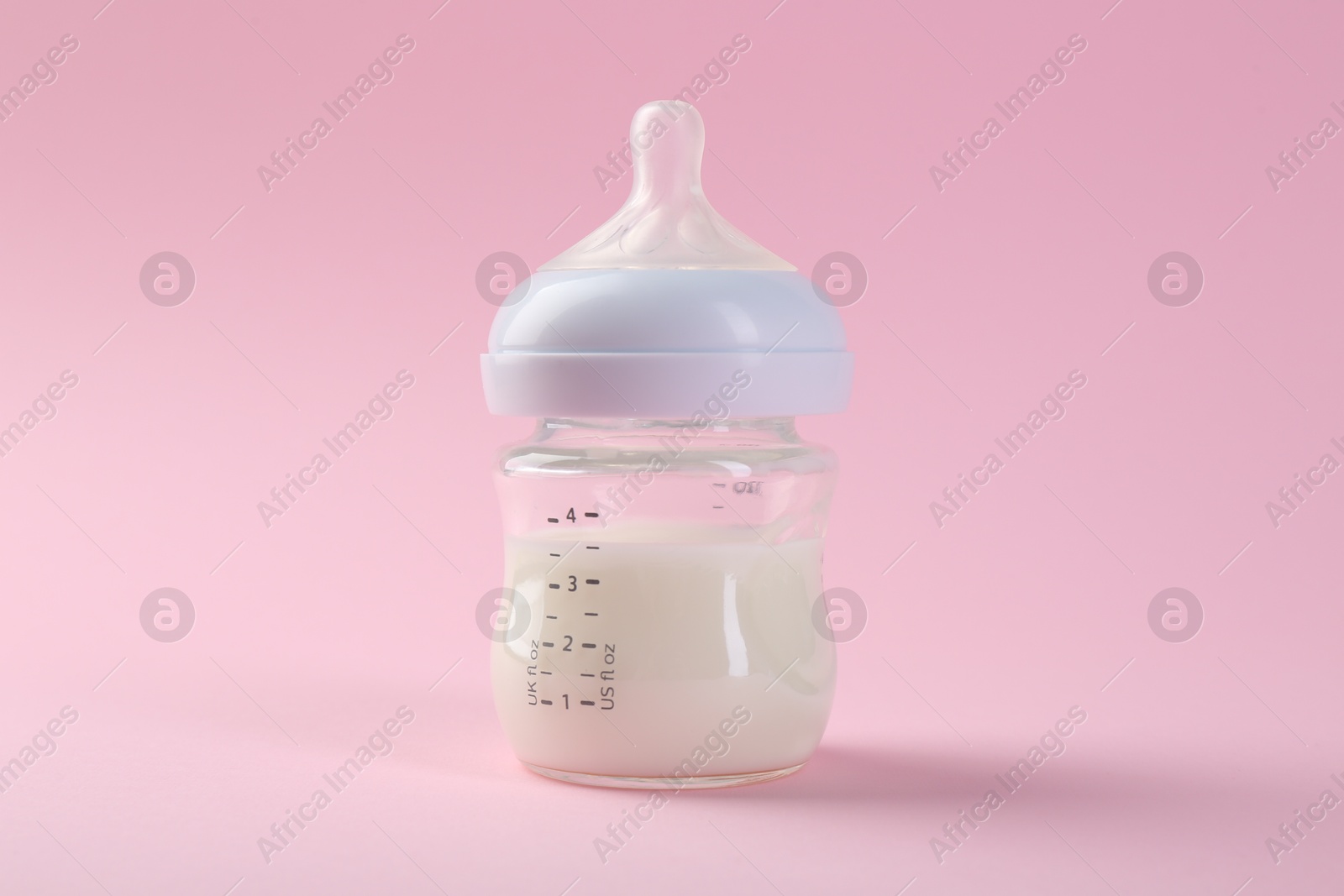 Photo of Feeding bottle with milk on pink background