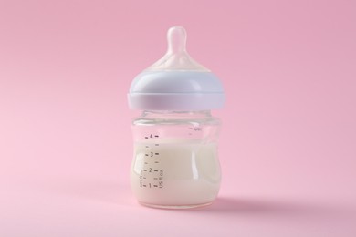 Feeding bottle with milk on pink background