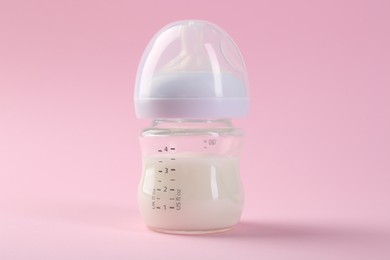 Photo of Feeding bottle with milk on pink background