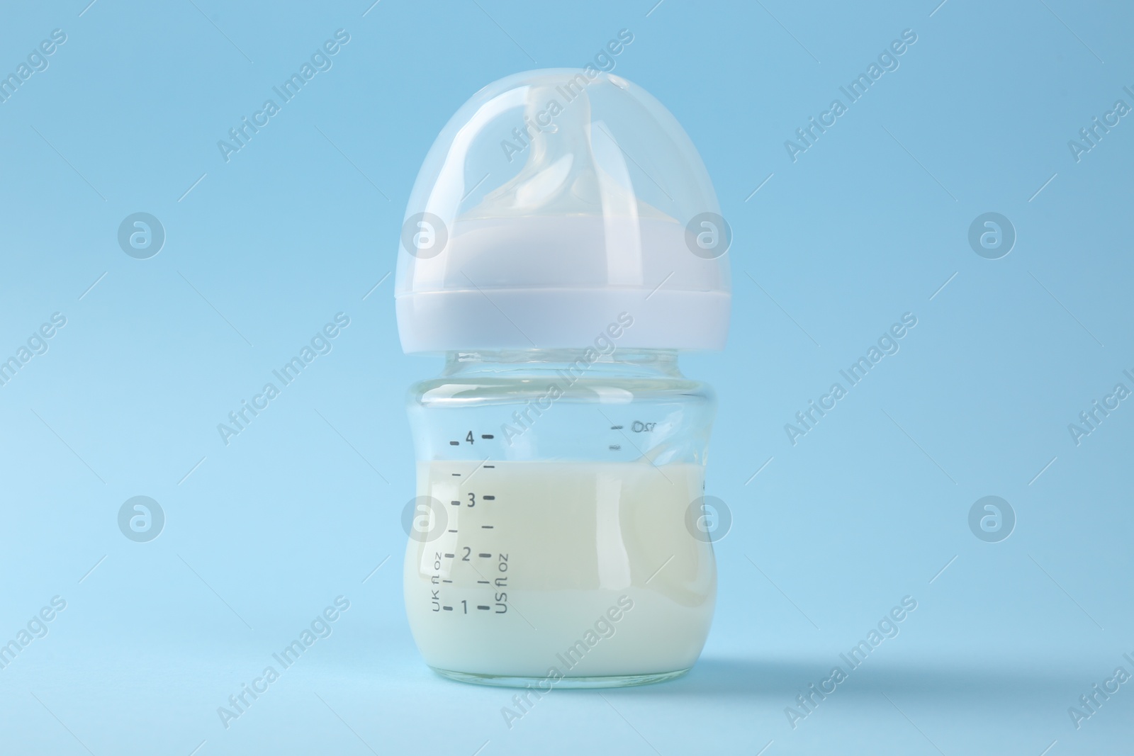 Photo of Feeding bottle with milk on light blue background