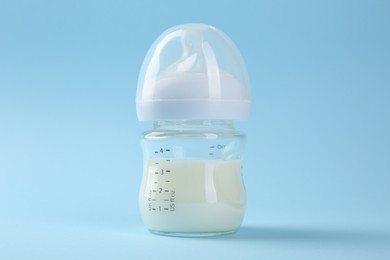 Feeding bottle with milk on light blue background