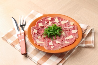 Photo of Fresh beef carpaccio with arugula and cheese on wooden table, closeup