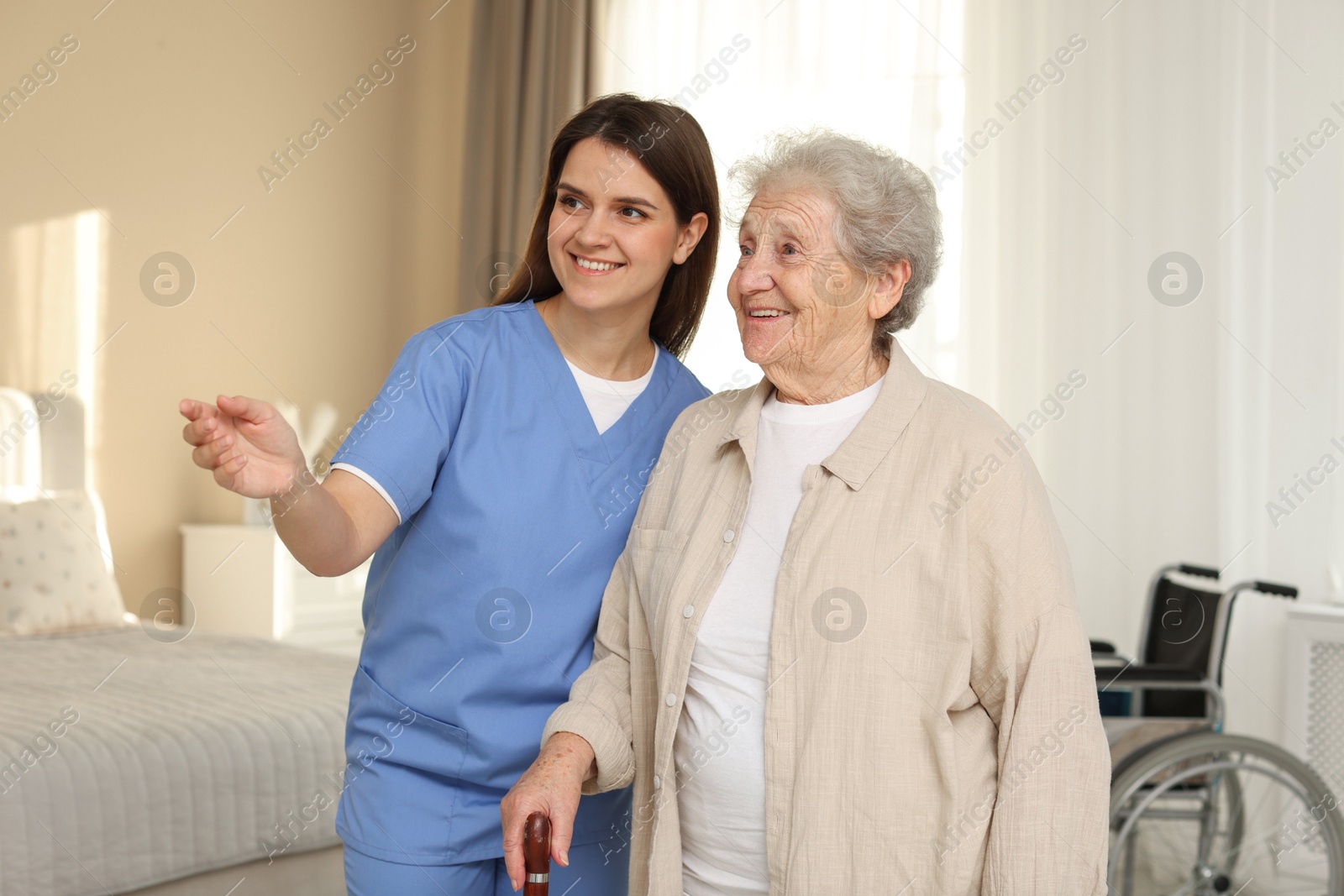 Photo of Smiling healthcare worker and elderly woman looking at something indoors