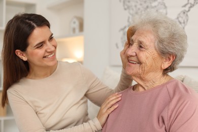 Photo of Granddaughter brushing her grandmother with comb at home. Elderly care