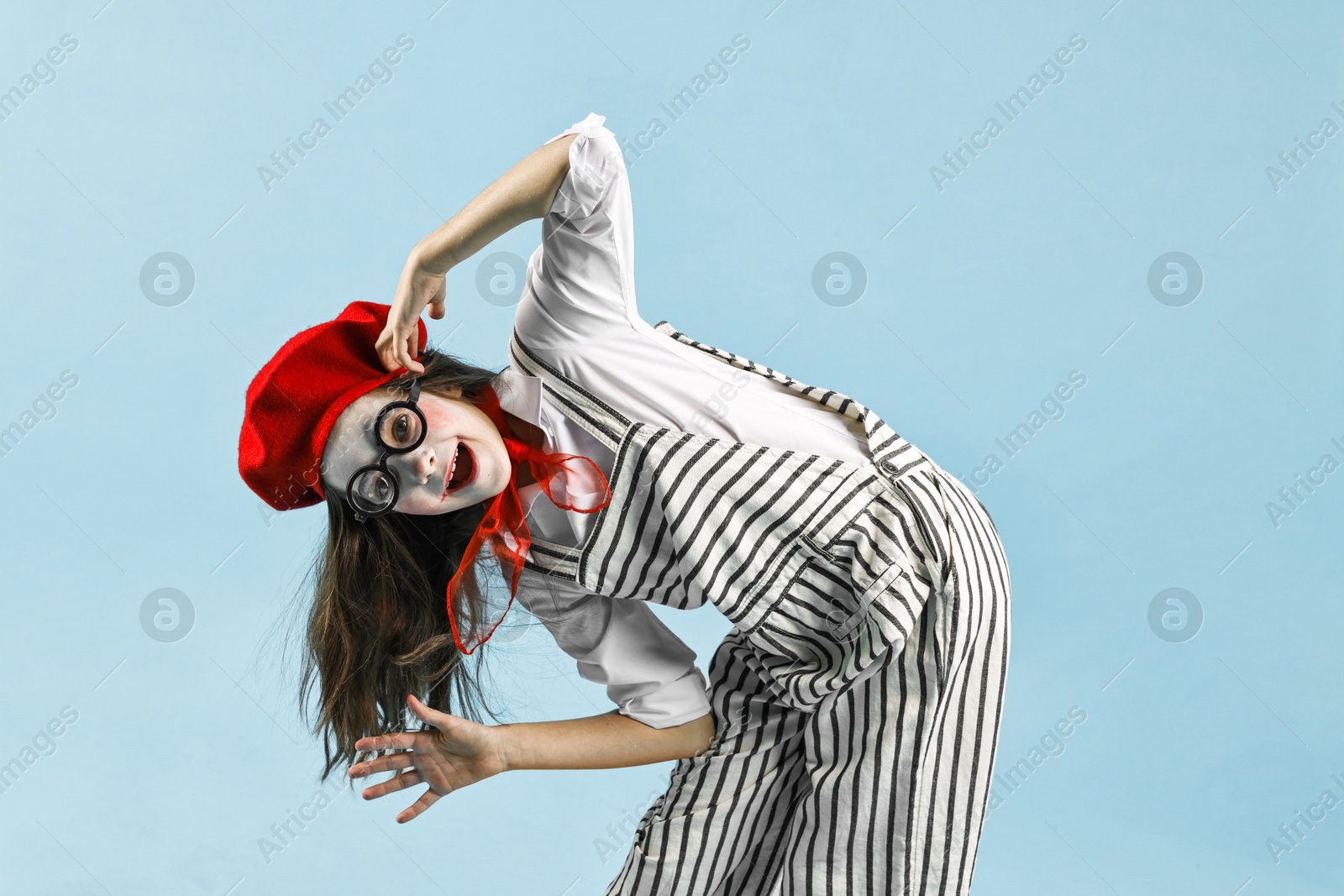 Photo of Happy girl dressed like mime on light blue background. Surprise party