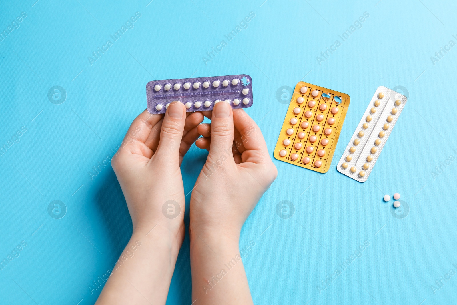 Photo of Woman with contraceptive pills on light blue background, closeup