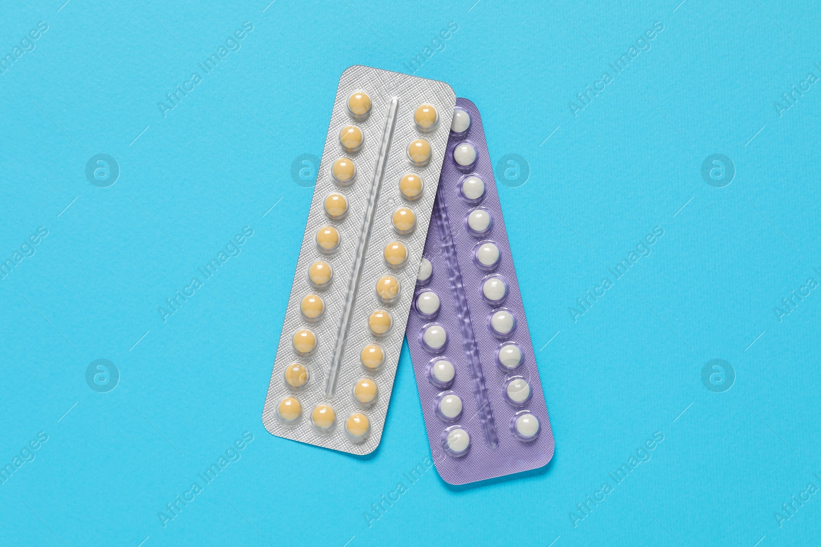 Photo of Blisters of contraceptive pills on light blue background, top view