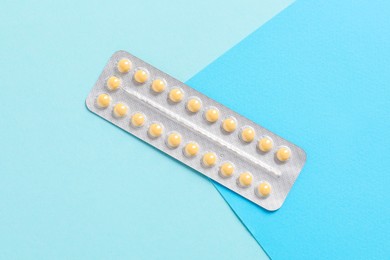 Photo of Blister of contraceptive pills on light blue background, top view