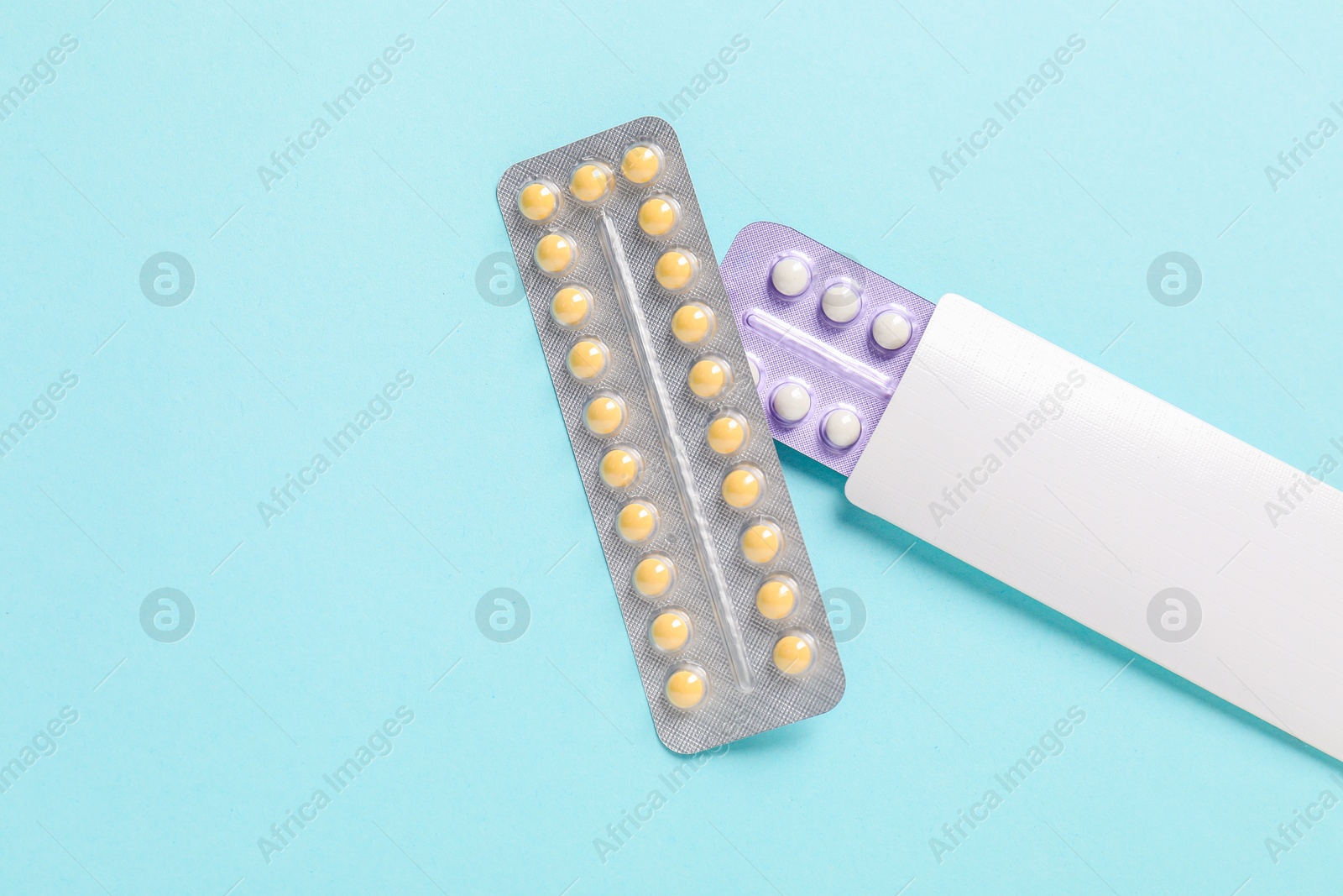 Photo of Blisters of contraceptive pills on light blue background, top view. Space for text