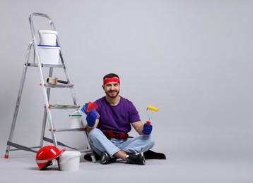 Photo of Man with tools and supplies on light grey background. Space for text