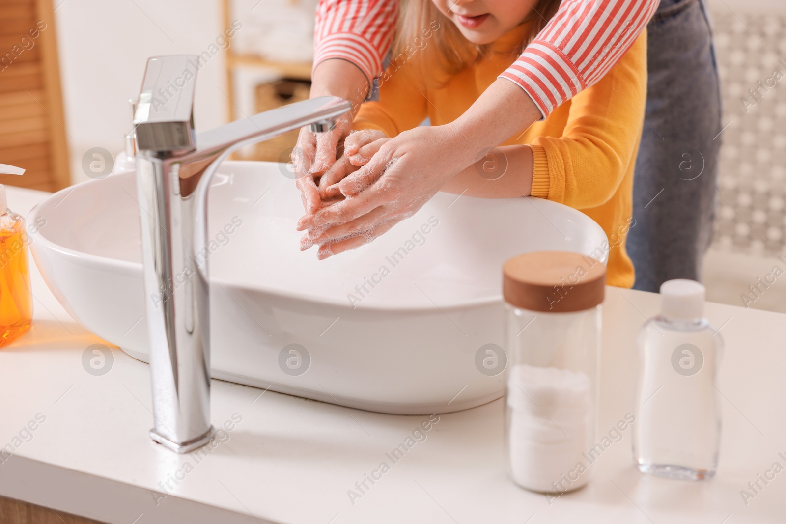 Photo of Mother and daughter washing their hands indoors, closeup