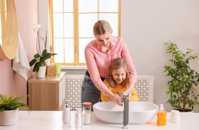 Mother and daughter washing their hands in bathroom