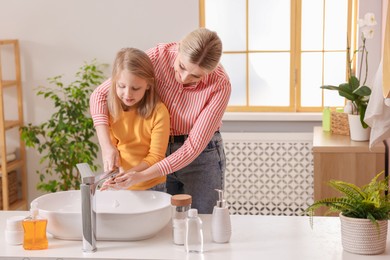 Mother and daughter washing their hands in bathroom