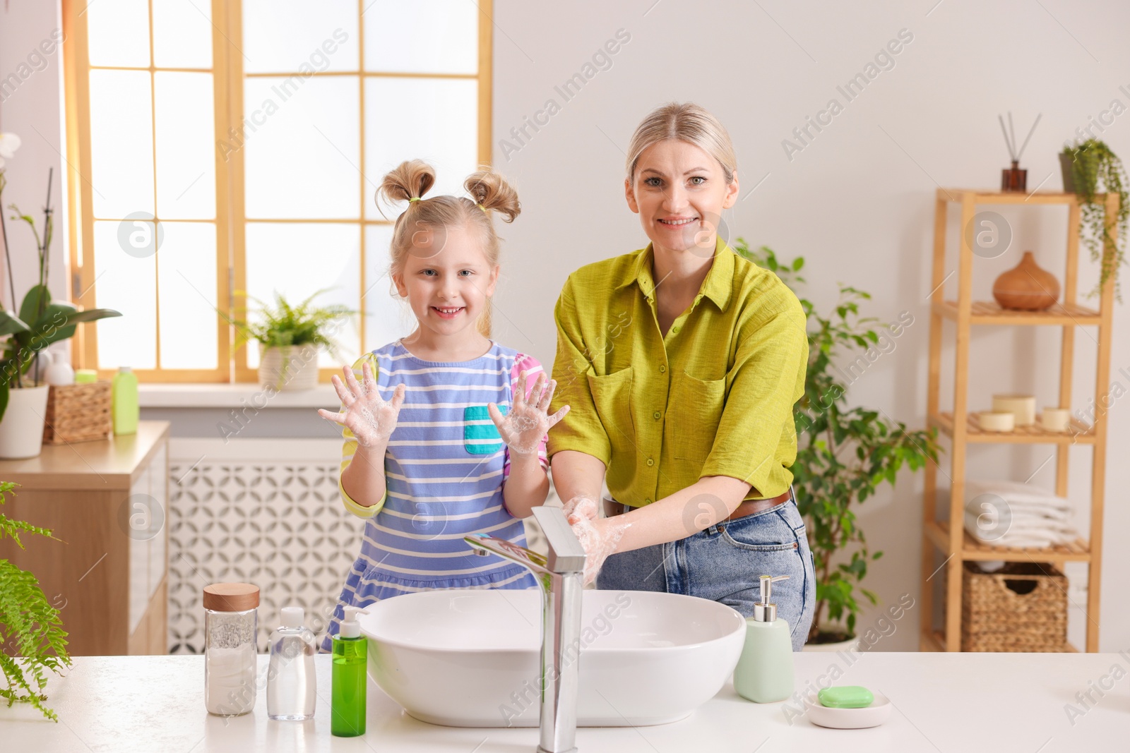 Photo of Happy mother and daughter washing their hands in bathroom