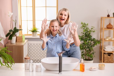 Photo of Happy mother and daughter washing their hands in bathroom