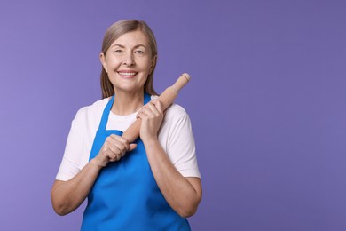 Photo of Happy woman with rolling pin on violet background. Space for text