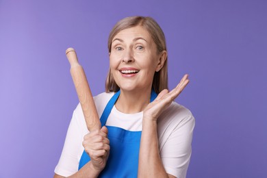 Photo of Happy woman with rolling pin on violet background