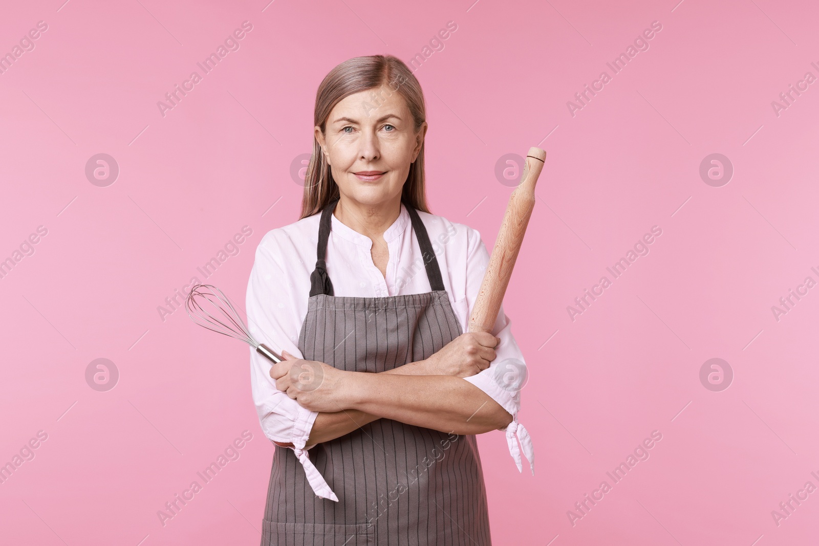 Photo of Woman with rolling pin and whisk on pink background